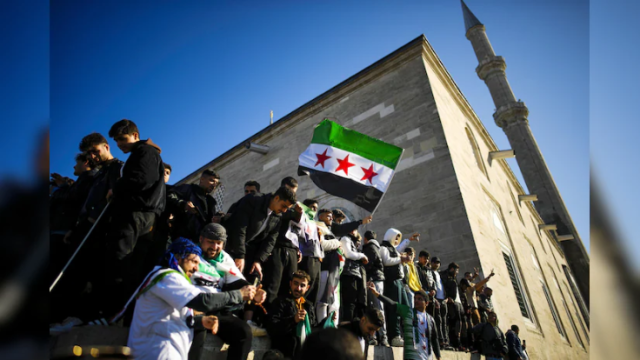 Photo of Members of the Syrian community wave Syria's national flags during a demonstration near Domplein to celebrate the end of the regime of Syrian dictator Bashar al-Assad after rebel fighters took control of the Syrian capital Damascus